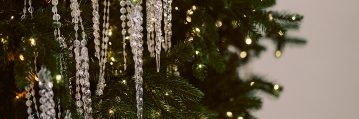 Close-up of a Christmas tree, adorned with shimmering crystal garlands. The decorations cast a magical glow on the dark green pine needles. Concept for holiday decorations and festive atmosphere.