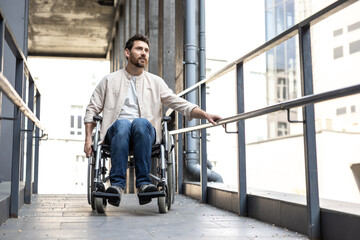 Fototapeta na wymiar Dark-haired young caucasian man riding a wheelchair
