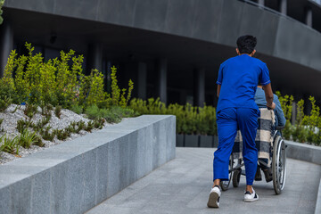 Man in wheelchair on a walk with a male nurse