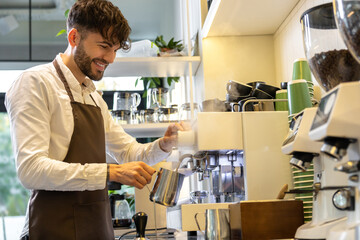 Smiling man barista brewing coffee in cafe smiling happily