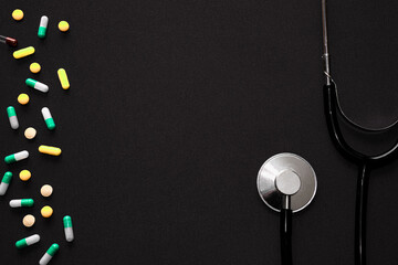 Medical pills, tonometer and stethoscope on the black surface. Blood pressure measurement. Color...