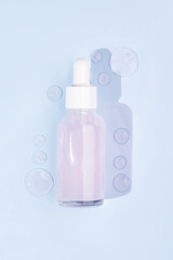 Top view of pink serum essence in glass bottle with smears on blue background. Isolated skincare oil. Beauty treatment