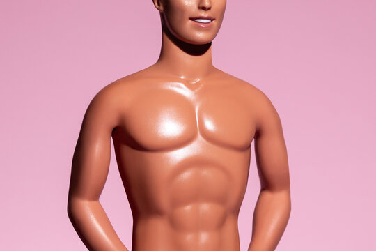 muscular body, athletic, tanned male torso of a handsome barbie ken plastic doll man close-up isolated on pink background, summer mood