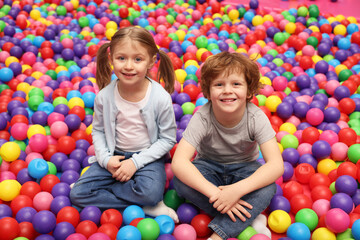 Fototapeta na wymiar Happy little kids sitting on colorful balls in ball pit