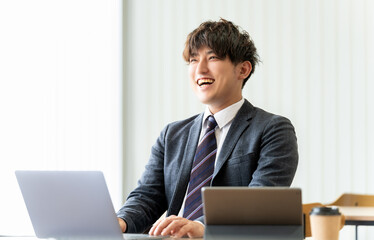笑顔でパソコンを使う男性ビジネスマン