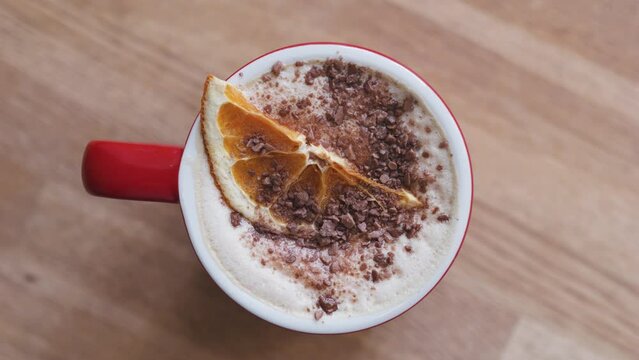 Cappuccino coffee hot chocolate with dried orange slice and grated chocolate.