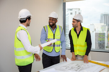 Construction engineer with technician designer team working build site inspect for interior renovate in industry workshop building with floor plan.