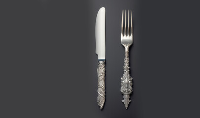 White vintage silver cutlery view from above on a grey background. Top view. Antique knife and fork for a festive table for a wedding, birthday or party.