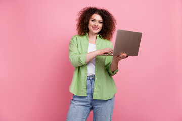 Photo portrait of lovely young lady hold netbook typing email dressed stylish green garment isolated on pink color background