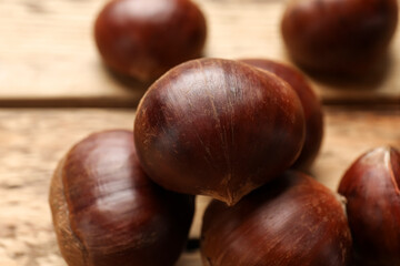 Sweet fresh edible chestnuts on wooden table, closeup