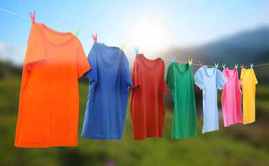 Different t-shirts drying on washing line outdoors, banner design