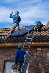 Three workers installing solar panels. Solar energy