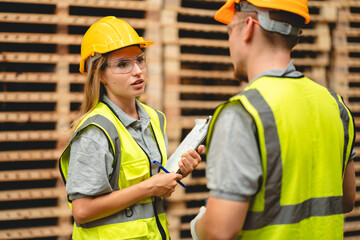 Man and woman workers with clipboard discussing working and checking stock inventory wood plank material for making wooden pallet products at warehouse industrial factory, woodwork production
