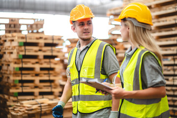 Man and woman workers with clipboard discussing working and checking stock inventory wood plank material for making wooden pallet products at warehouse industrial factory, woodwork production