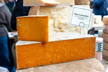 The large slab of red Leicester cheese. It is made from British cow milk, unpasteurised. It is a hard cheese known as Leicestershire cheese or red Leicester. A moist, crumblier with a milder flavour