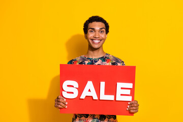 Photo of young positive guy holding red bright placard sale slogan for boutique summer accessories...
