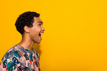 Obraz premium Side profile photo of excited crazy funny young man in t shirt screaming empty space announcing isolated on yellow color background