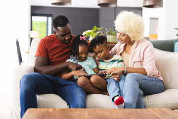 African American parents enjoy time with their daughter and son, all focused on a tablet