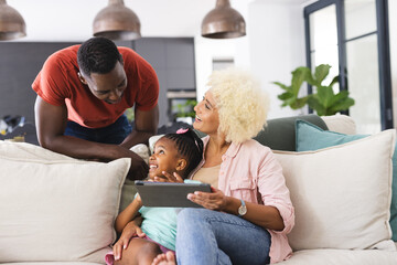 African American father and mother enjoy time with their daughter, using a tablet