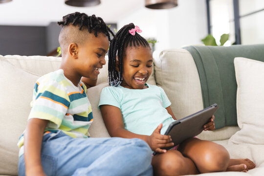 African American sister and brother are sharing a joyful moment with a tablet