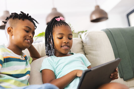 African American brother and sister are focused on a tablet indoors