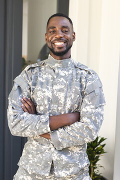 African American man in military uniform smiles confidently, arms crossed