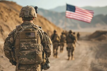 U.S. troops in the middle of their mission, walking through the field with their equipment and the American flag - obrazy, fototapety, plakaty