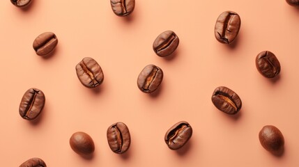 Coffee beans scattered on a peach background. Isolated on a solid color background. Perfect for use in food and beverage advertising, packaging design, or as a background for text.