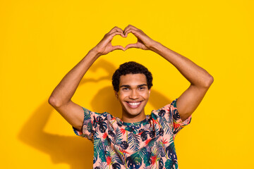 Portrait of young cheerful funny guy in t shirt showing heart symbol romantic boyfriend smiling...