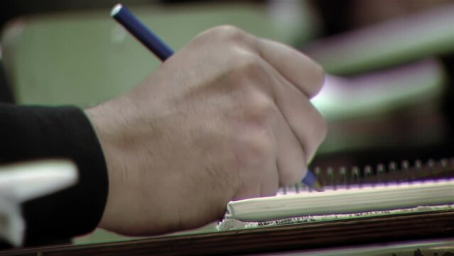 Hand of a Male Student Writing in A Spiral Notebook While Taking An Exam at College. Close Up.  