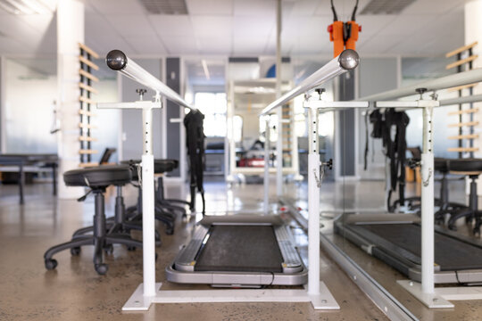 A treadmill flanked by mobility assistance equipment dominates the foreground