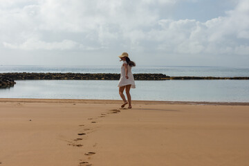 Woman with hat dancing on a paradisiacal beach.dng