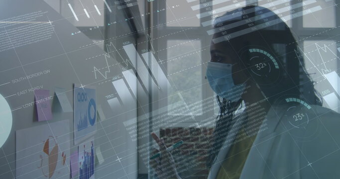 Image of financial data processing over businesswoman wearing face mask - Powered by Adobe