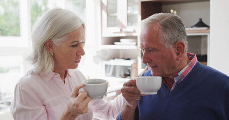 Image of hearts icons over happy senior caucasian couple drinking tea