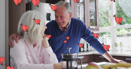 Image of hearts over happy senior caucasian couple drinking coffee