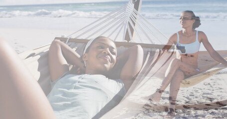 Image of happy african american woman in hammock on beach