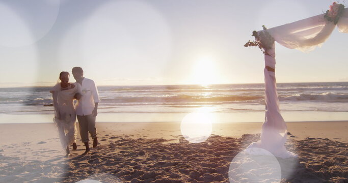 Image of dots over happy african american newly married couple on beach