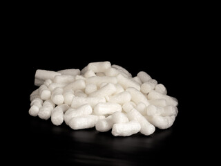 White expanded foam packing peanuts isolated on a black background
