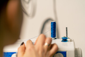 close-up in a sewing workshop on a machine winding blue thread on drum for sewing