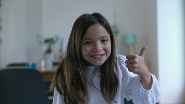 One excited little girl giving thumbs up to camera smiling, 8 year old child showing sign of approval