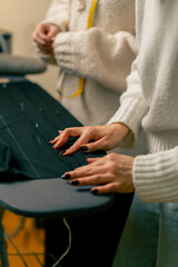 close up in a sewing workshop a seamstress pins a corrugated pin on a black fabric