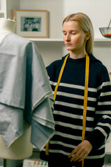 close-up in a sewing workshop a seamstress looks at mannequin with a cloth draped over it