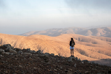 Una mujer visitando el mirador en Fuerteventura y disfrutando de la grandeza de las montañas áridas y bonitas