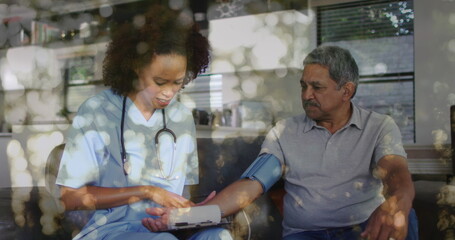 Image of bokeh over diverse doctor and patient measuring blood pressure