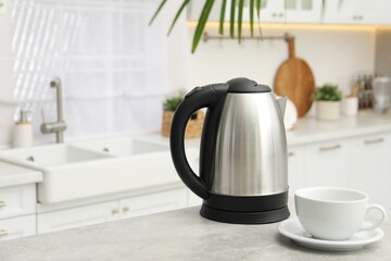 Electric kettle and cup on table in kitchen. Space for text