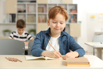 Fototapeta na wymiar Portrait of cute little boy studying in classroom at school