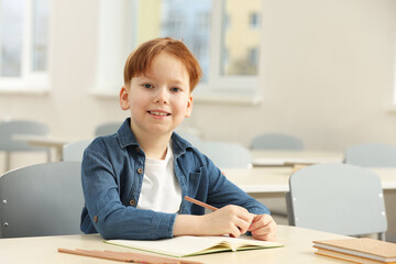 Naklejka premium Portrait of smiling little boy studying in classroom at school. Space for text