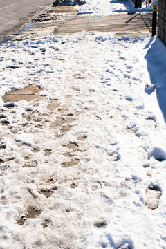 Unshoveled sidewalk with footprints in the snow