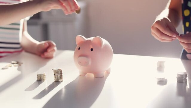 Children put coins in a piggy bank. Financial planning concept.