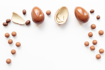 Chocolate eggs broken on white background. Chocolate sweets, top view